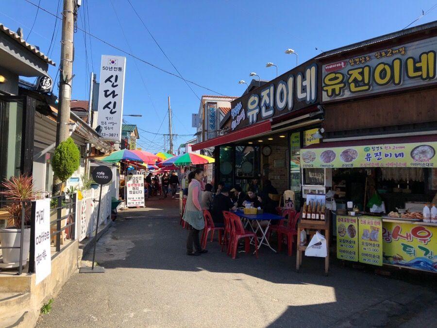 阿爸村的商品攤位和遊客，享受束草的當地風情與特色產品。